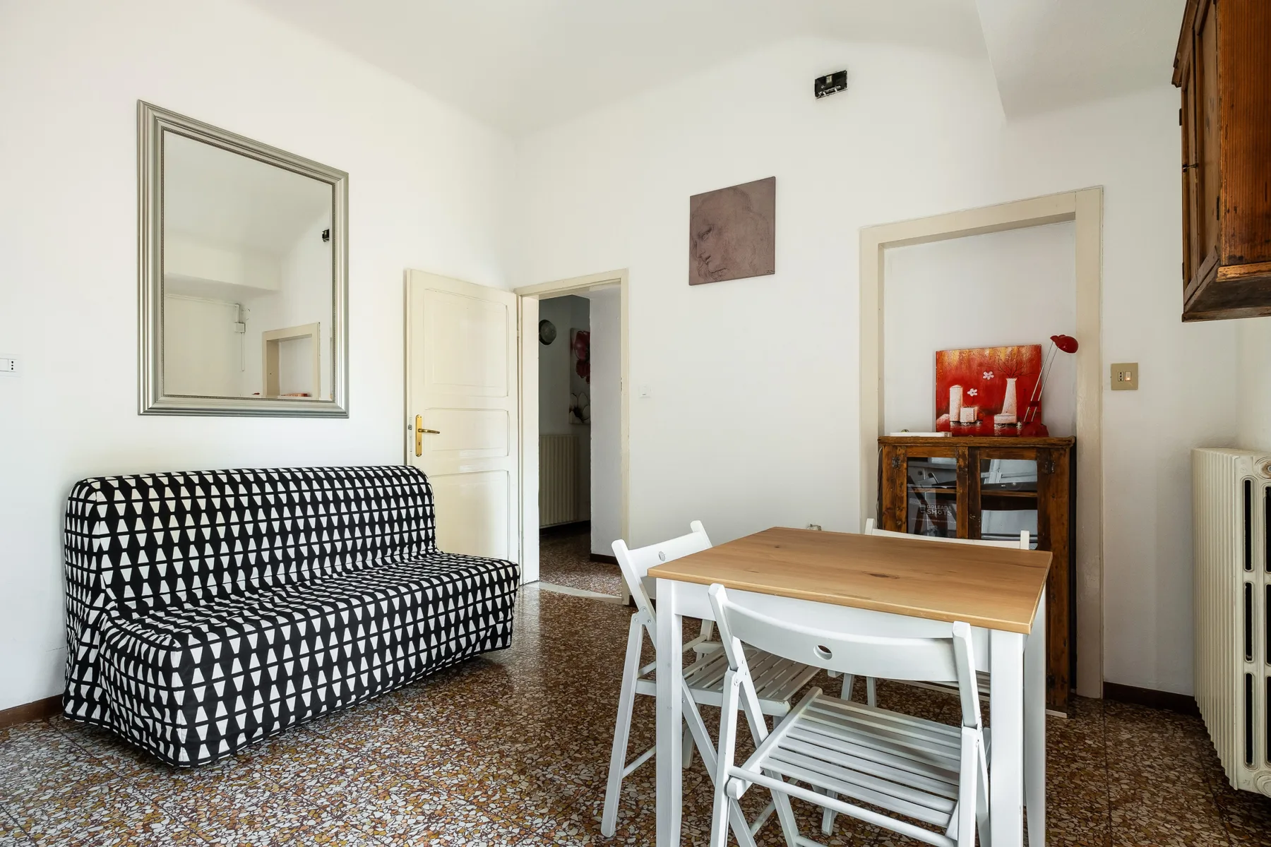 A bright dining and sitting room with a wooden table and patterned seating.
