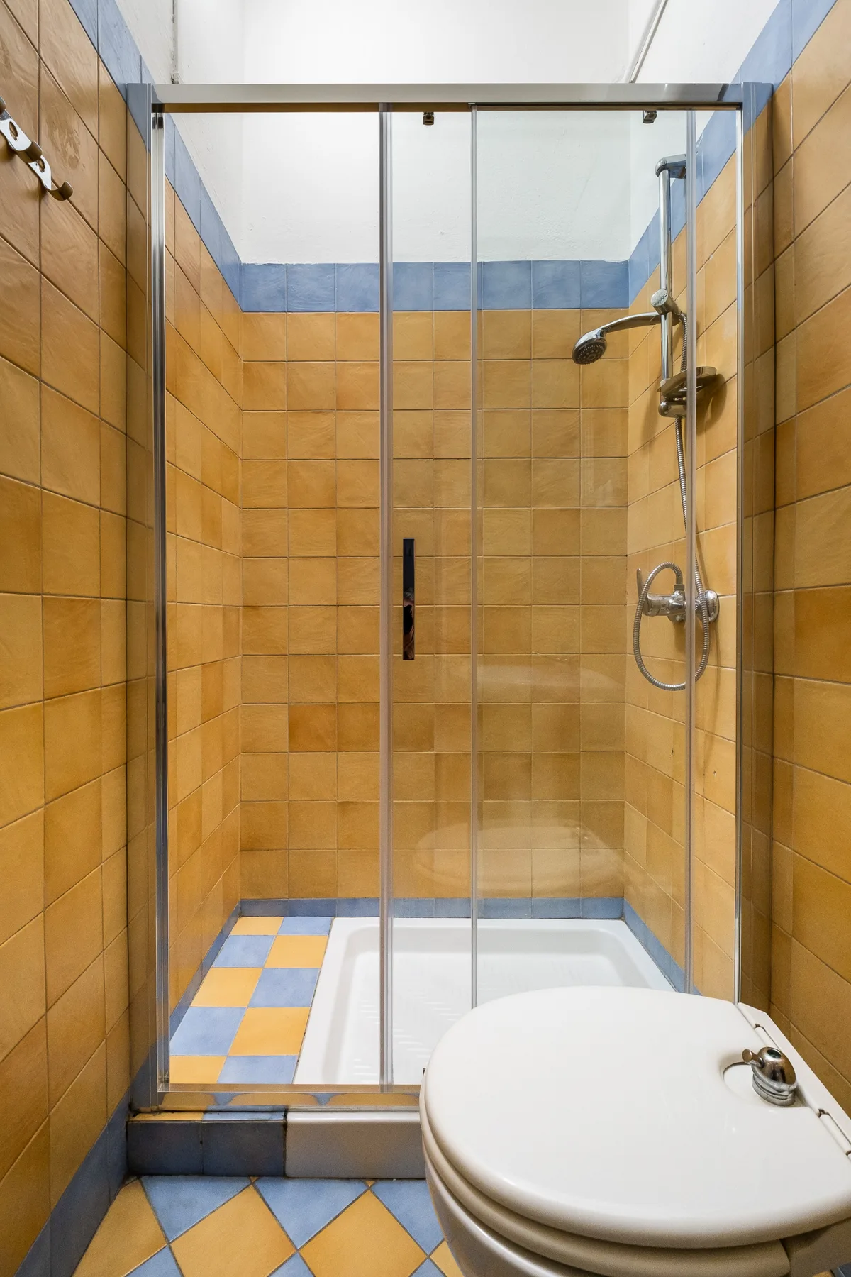 A tiled bathroom with a glass shower and a toilet.