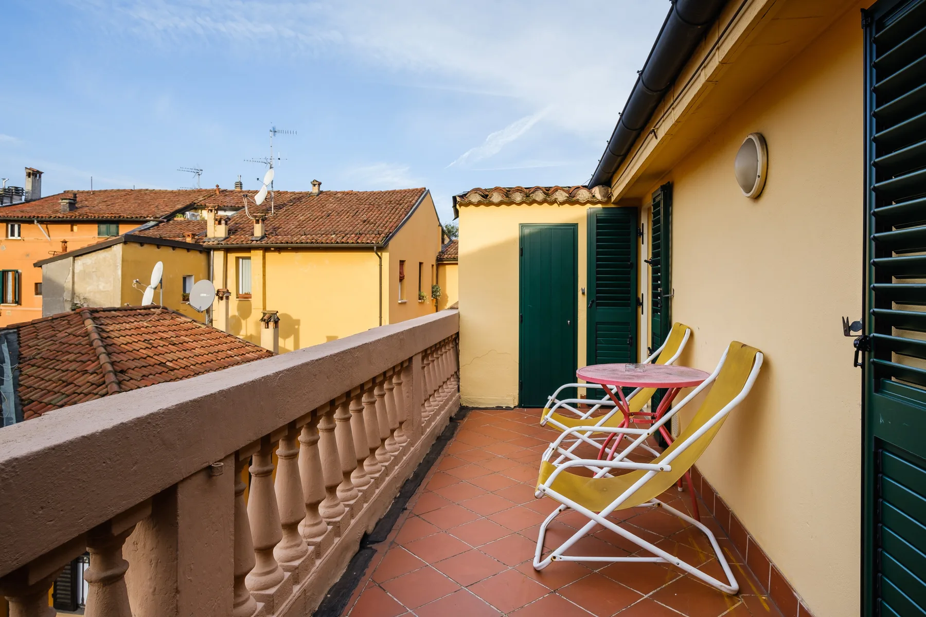 A tiled balcony with outdoor seating overlooks neighboring rooftops.