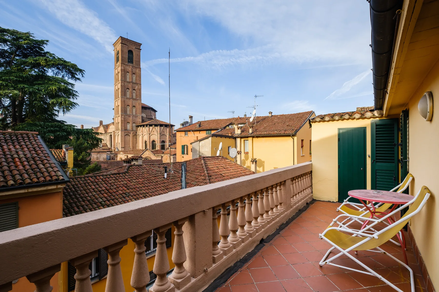 A tiled rooftop terrace overlooks neighboring buildings and a prominent brick tower.