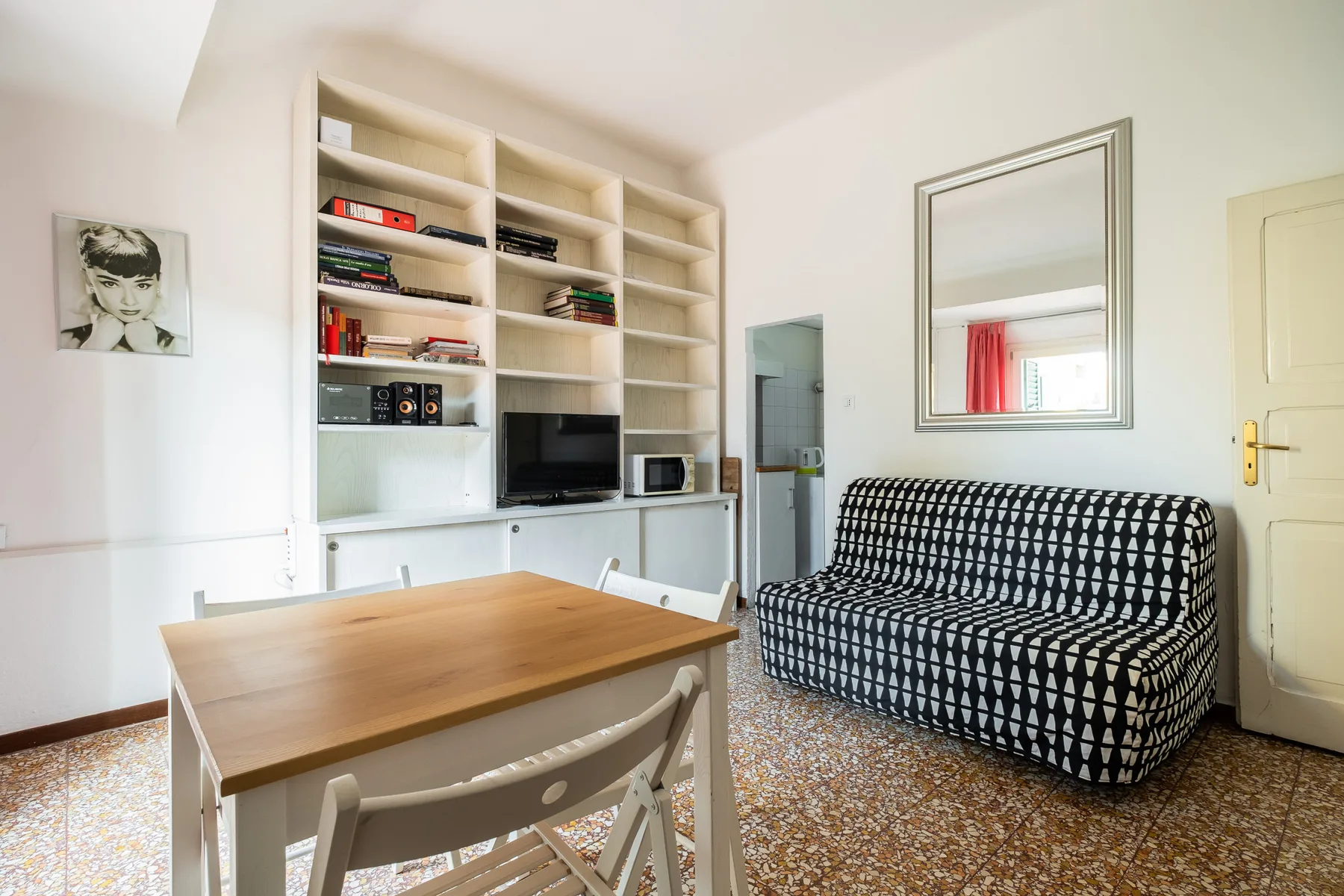 A living room with a patterned sofa, built-in shelves, and a wooden table.