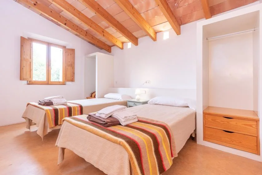A bedroom with two beds and a wooden ceiling.