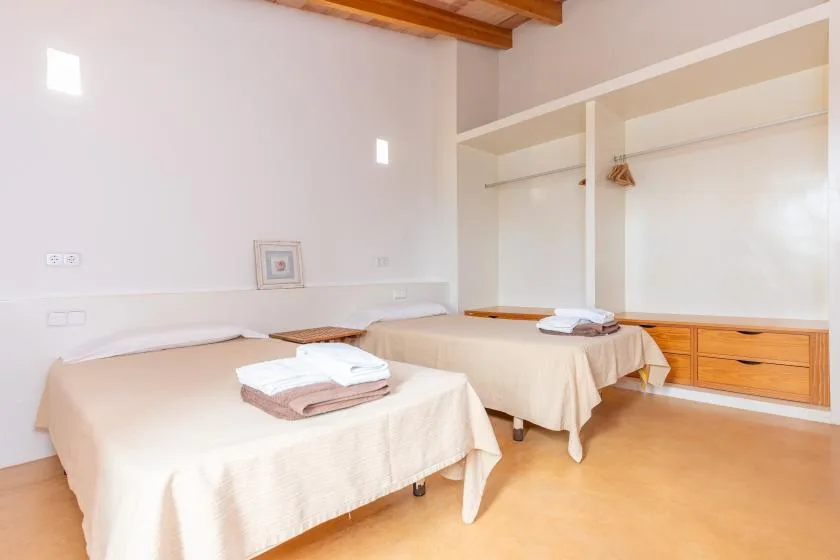 A bright bedroom with two beds dressed in light-colored linens.