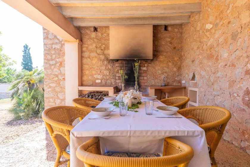 A covered outdoor dining area with a long table set beside stone walls.