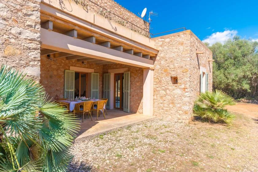 A stone house with a shaded patio and outdoor dining table.