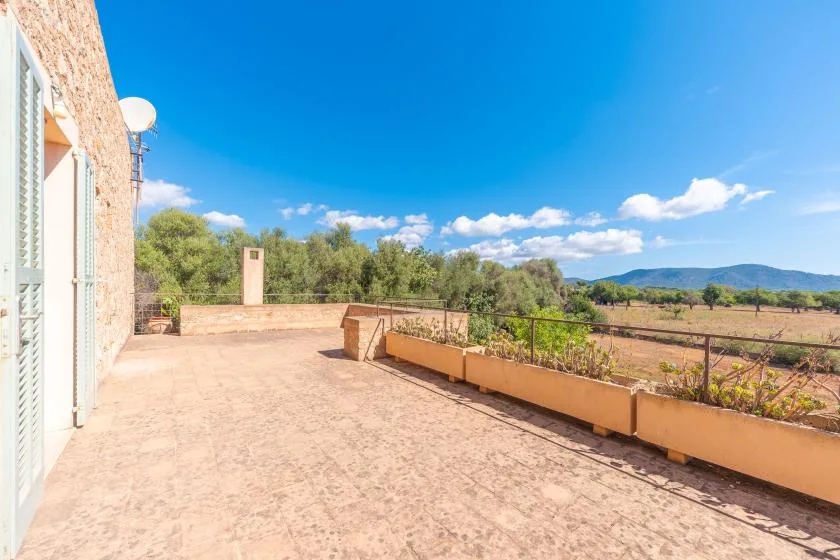 A spacious outdoor terrace with a long planter and open landscape views.