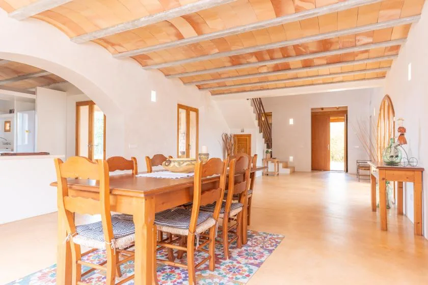A dining area with a wooden table and chairs beneath exposed ceiling beams.