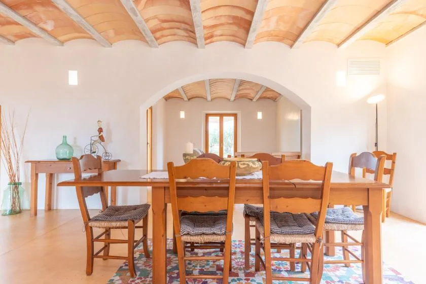 A dining area with a long wooden table and chairs beneath an arched opening.