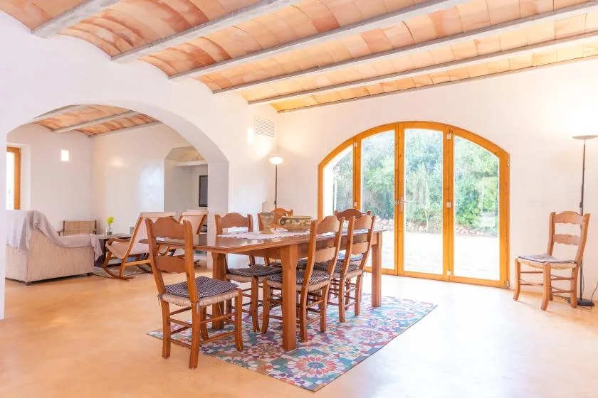 A bright dining area with a wooden table, chairs, and arched glass doors.