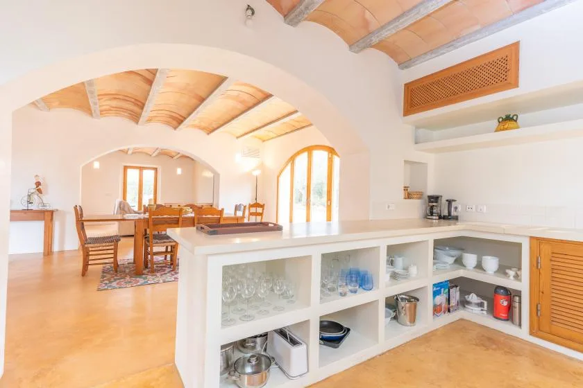 An open kitchen and dining area with a long counter and wooden ceiling beams.