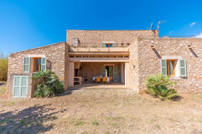 A stone house exterior with a shaded patio and outdoor seating.