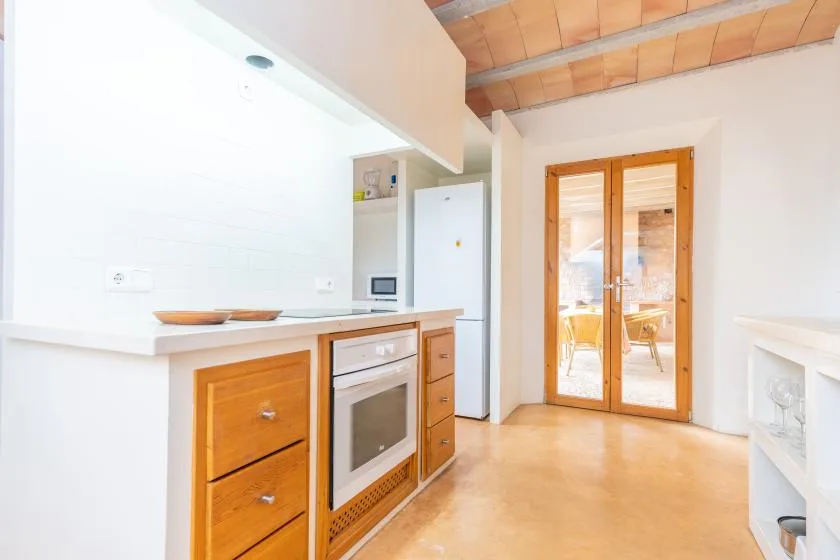 A bright kitchen with wooden cabinets and glass doors opening onto a dining area.