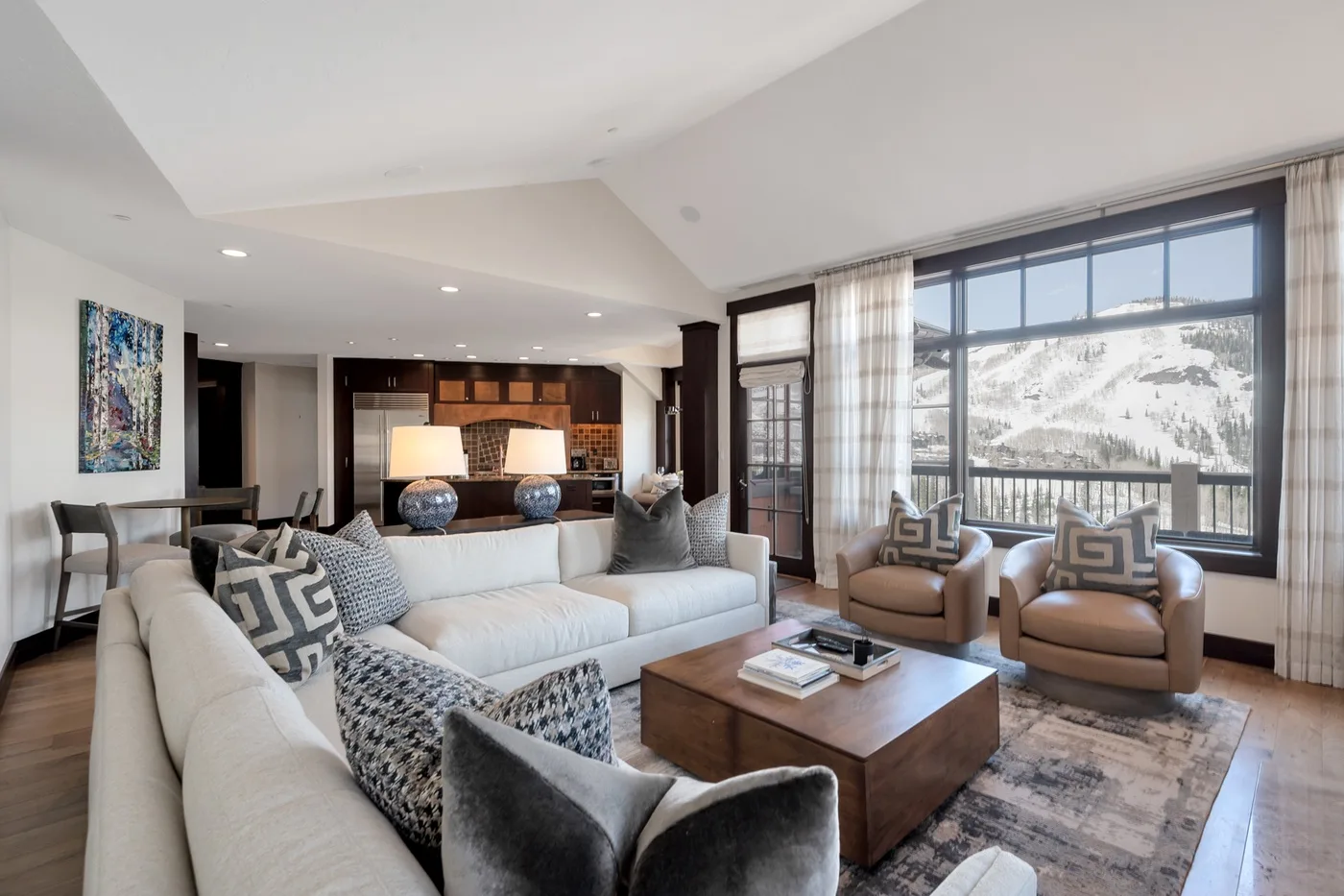 A bright living room with a large seating area and windows overlooking a snowy landscape.