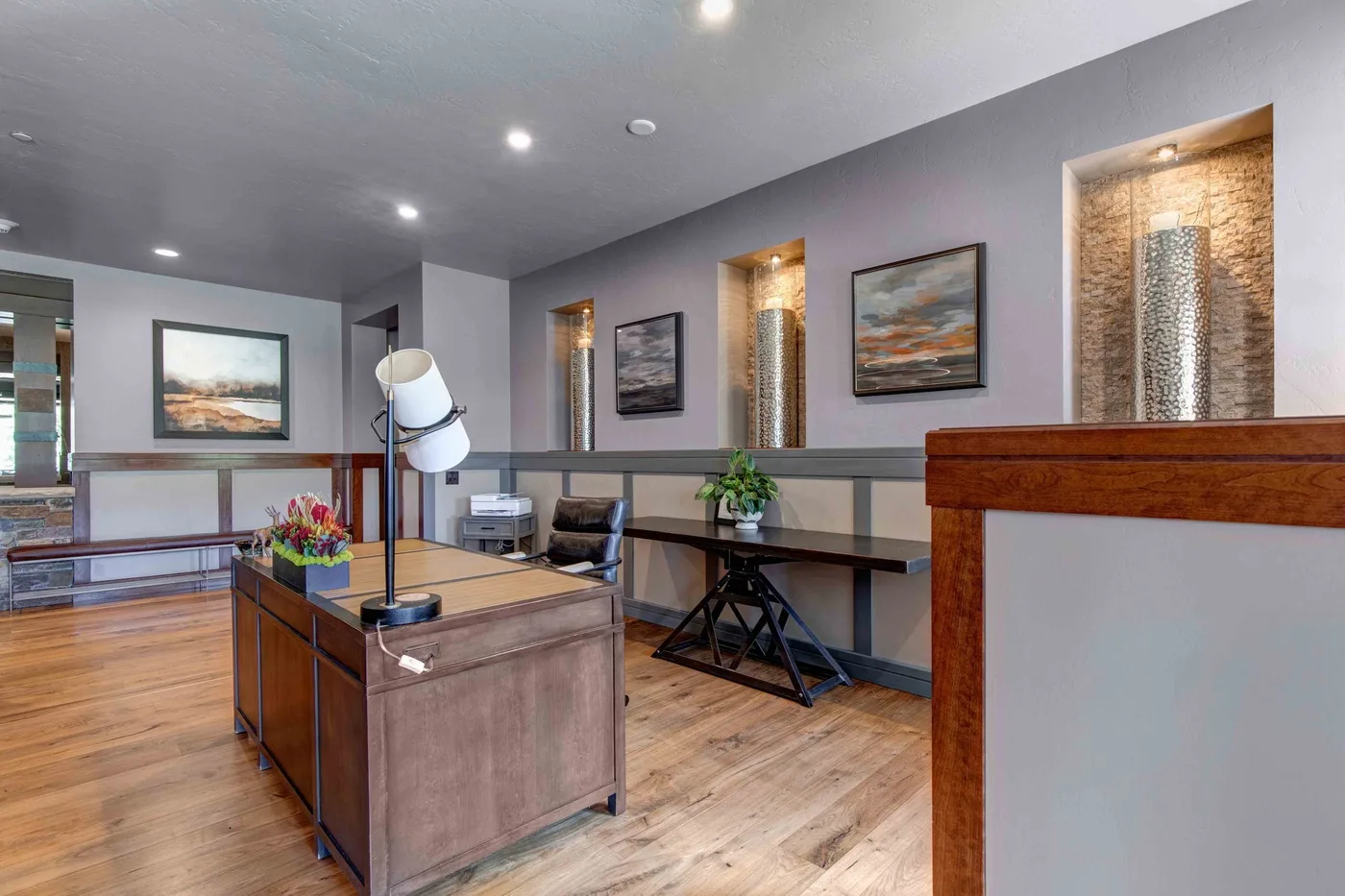 An office reception area with a wooden desk, seating, and framed artwork.