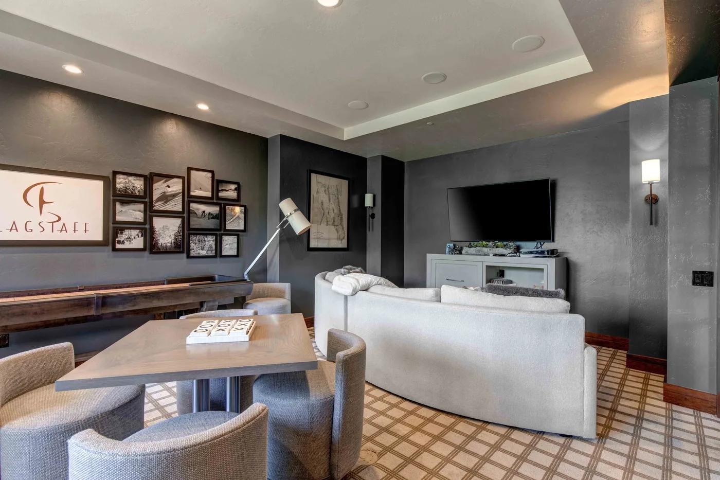 A modern living room with seating, a television, and framed wall art.