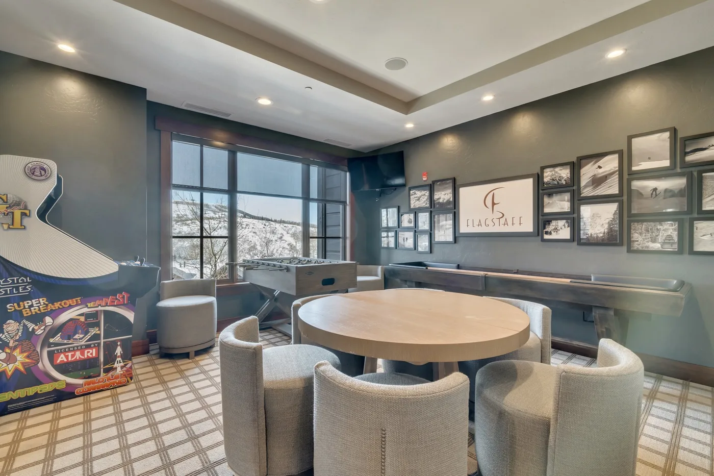 A lounge with a round table and seating beside large windows.