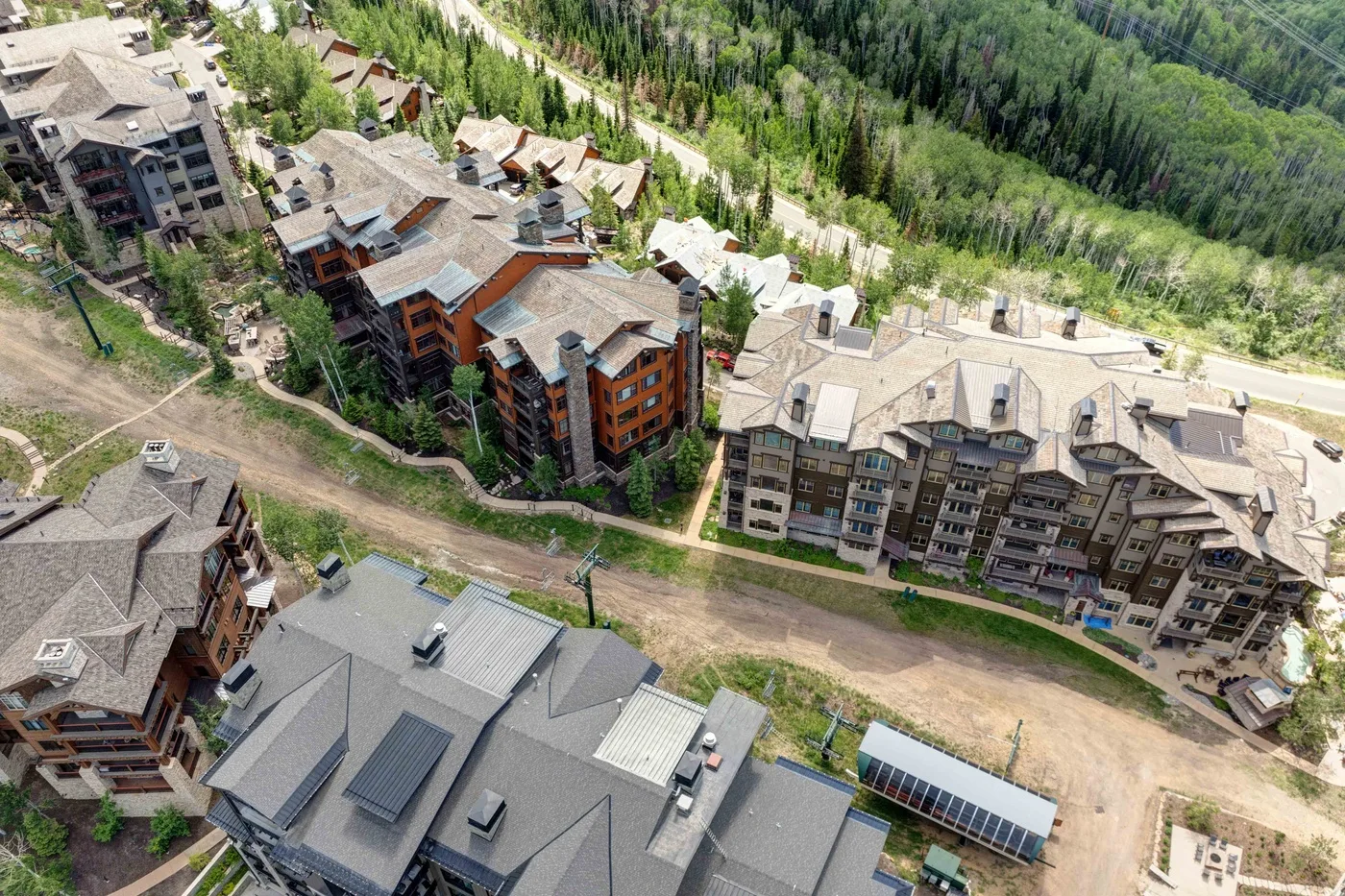 Aerial view of multi-story buildings beside a wooded hillside.