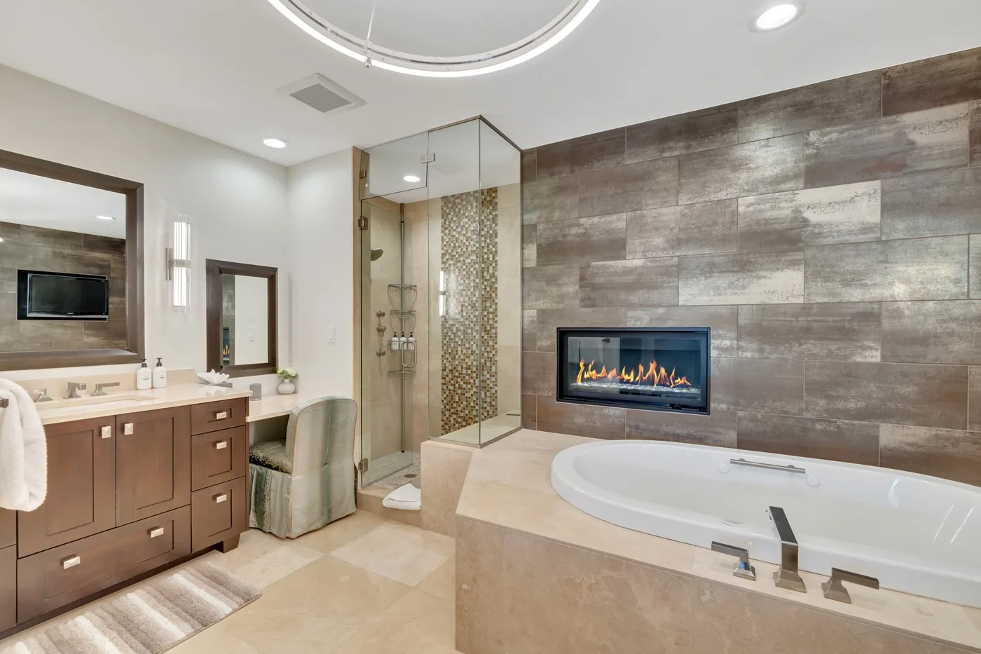 A spacious bathroom with a soaking tub, glass shower, and fireplace.