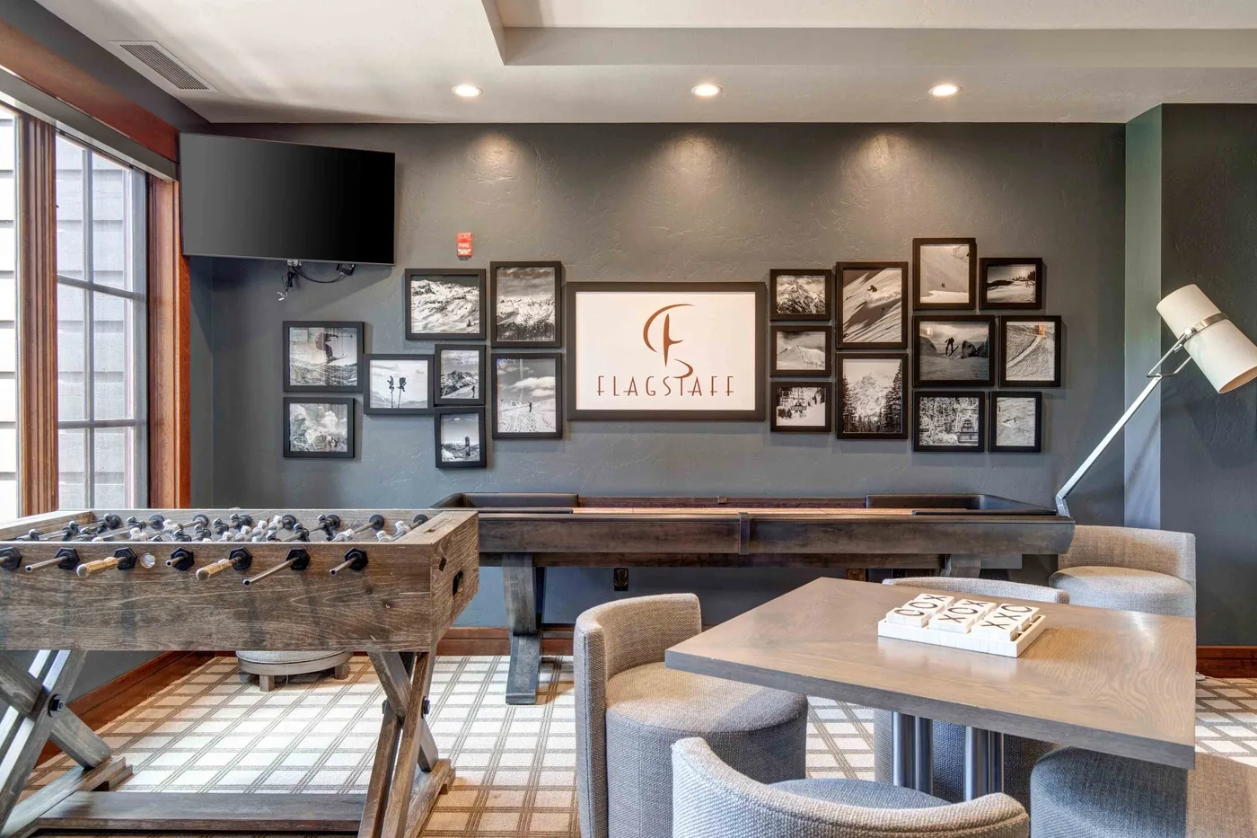 A game room features a foosball table, wall-mounted television, and seating.