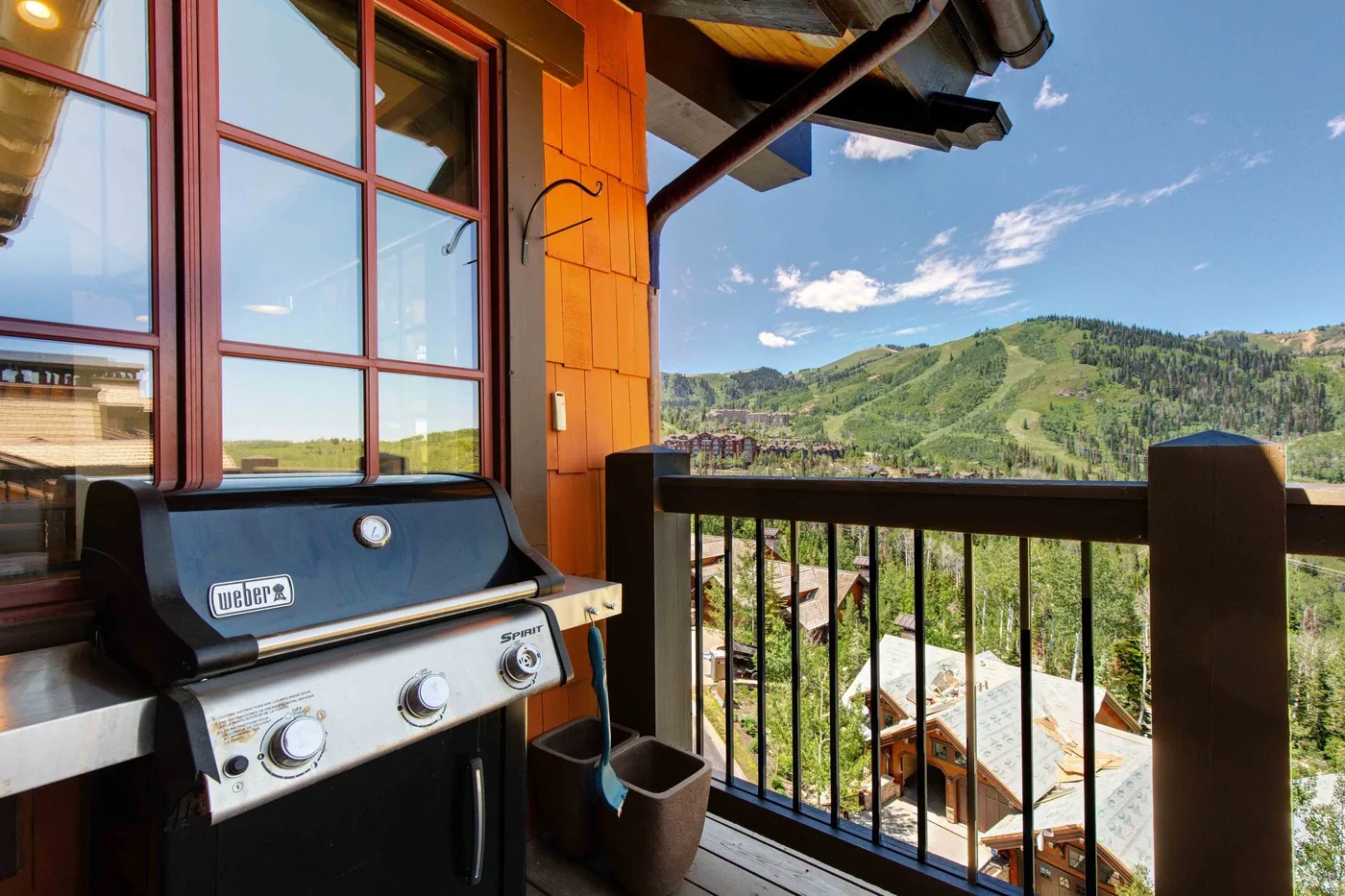 A balcony with a barbecue grill overlooks a green hillside.