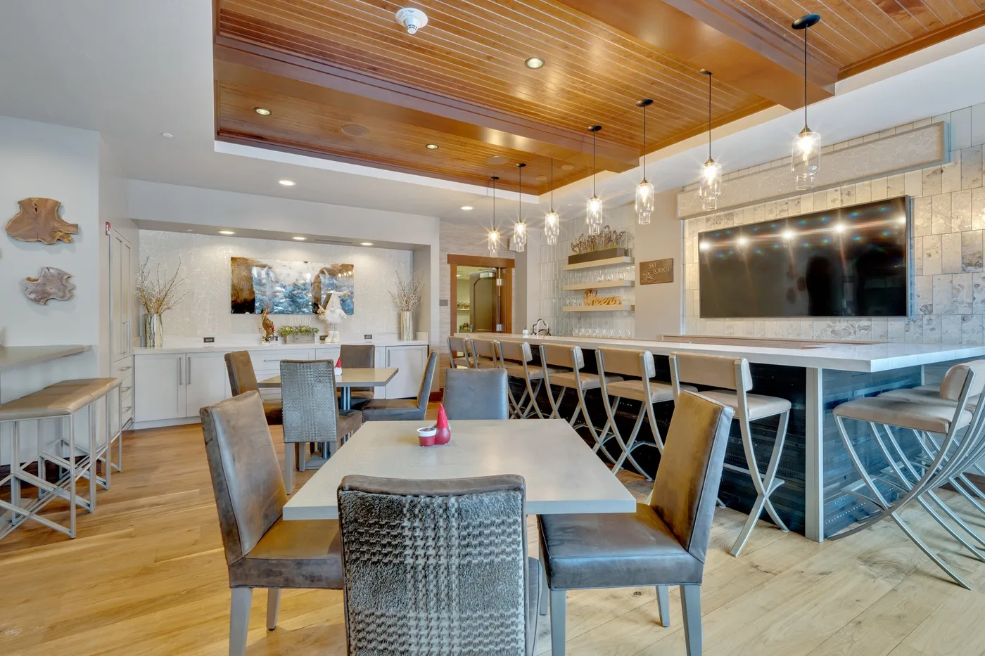 A dining area with tables and seating beneath a wood-paneled ceiling.