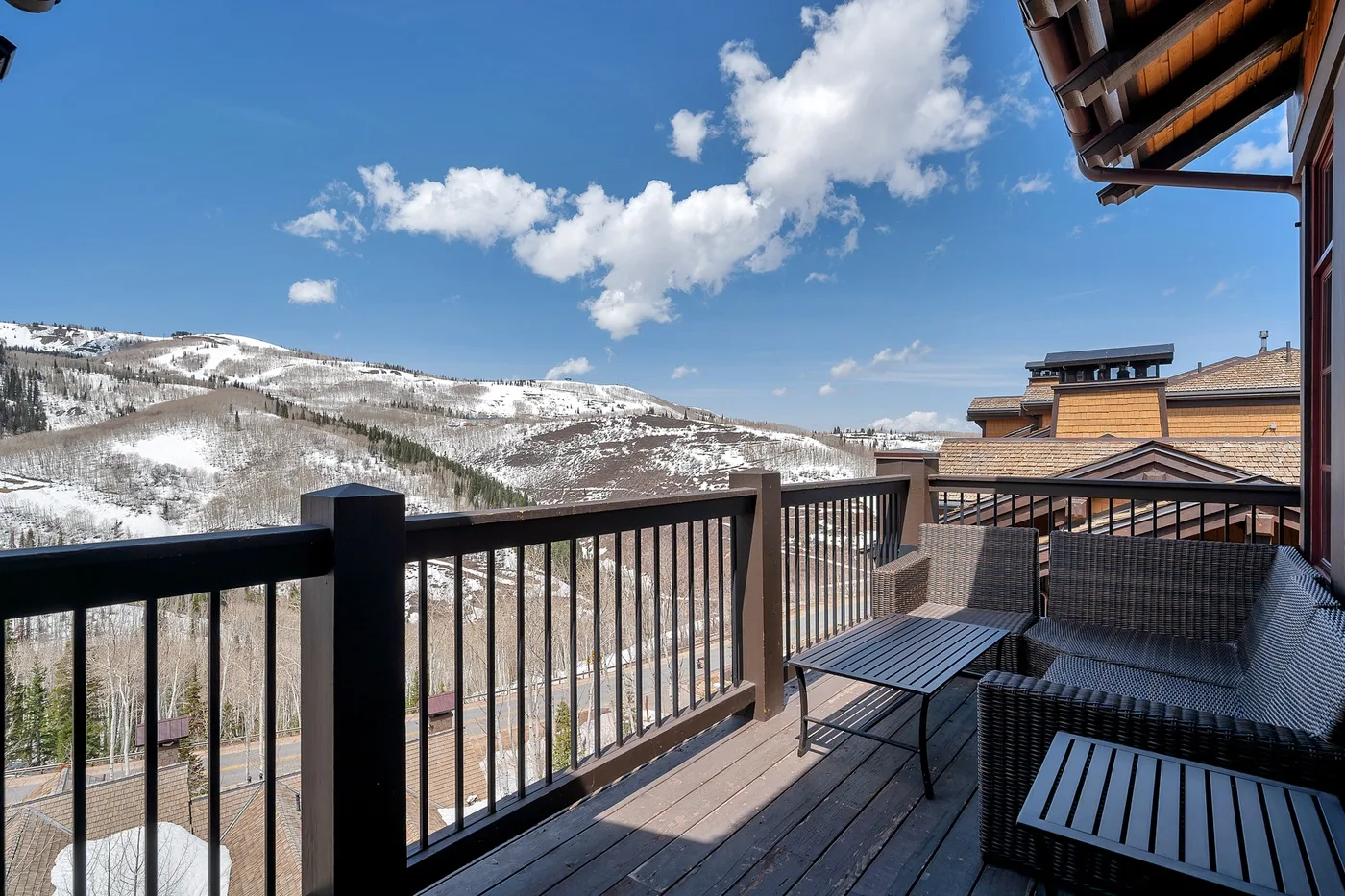 A balcony with outdoor seating overlooks a snow-dusted mountain landscape.