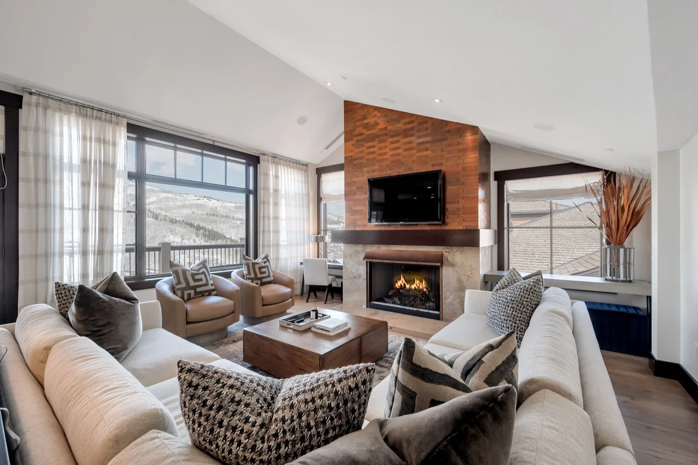 A bright living room with seating arranged around a fireplace and television.