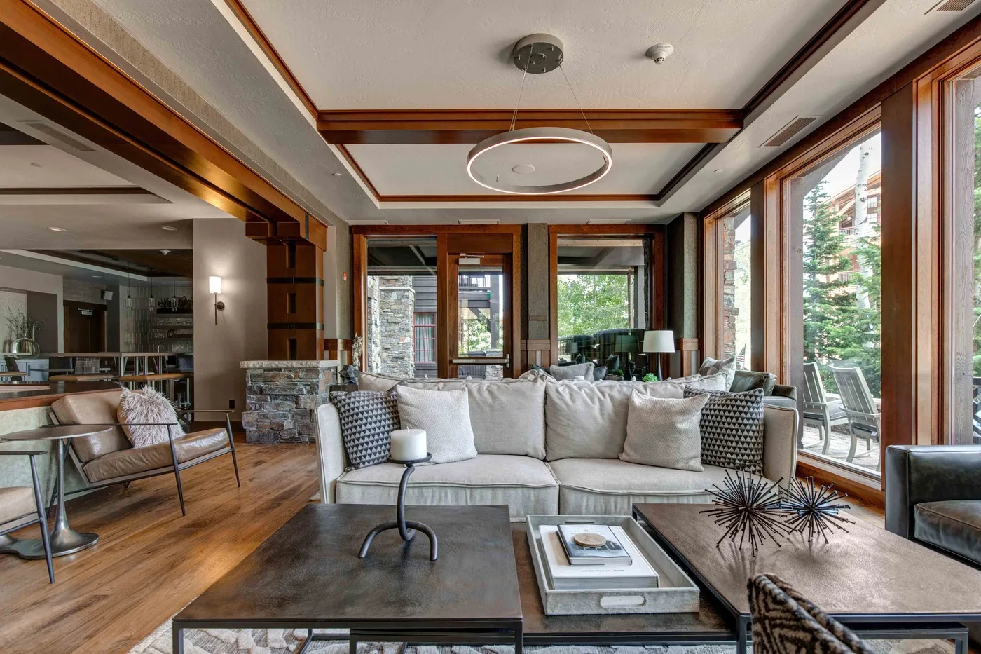 A bright living room with seating arranged around a coffee table beside large windows.