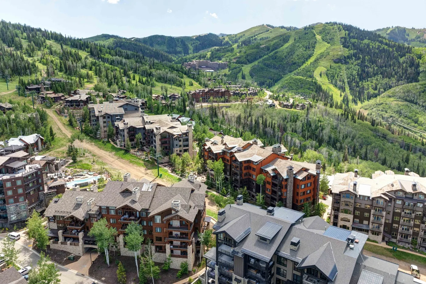 A mountain resort neighborhood with clustered buildings and green hills in the background.