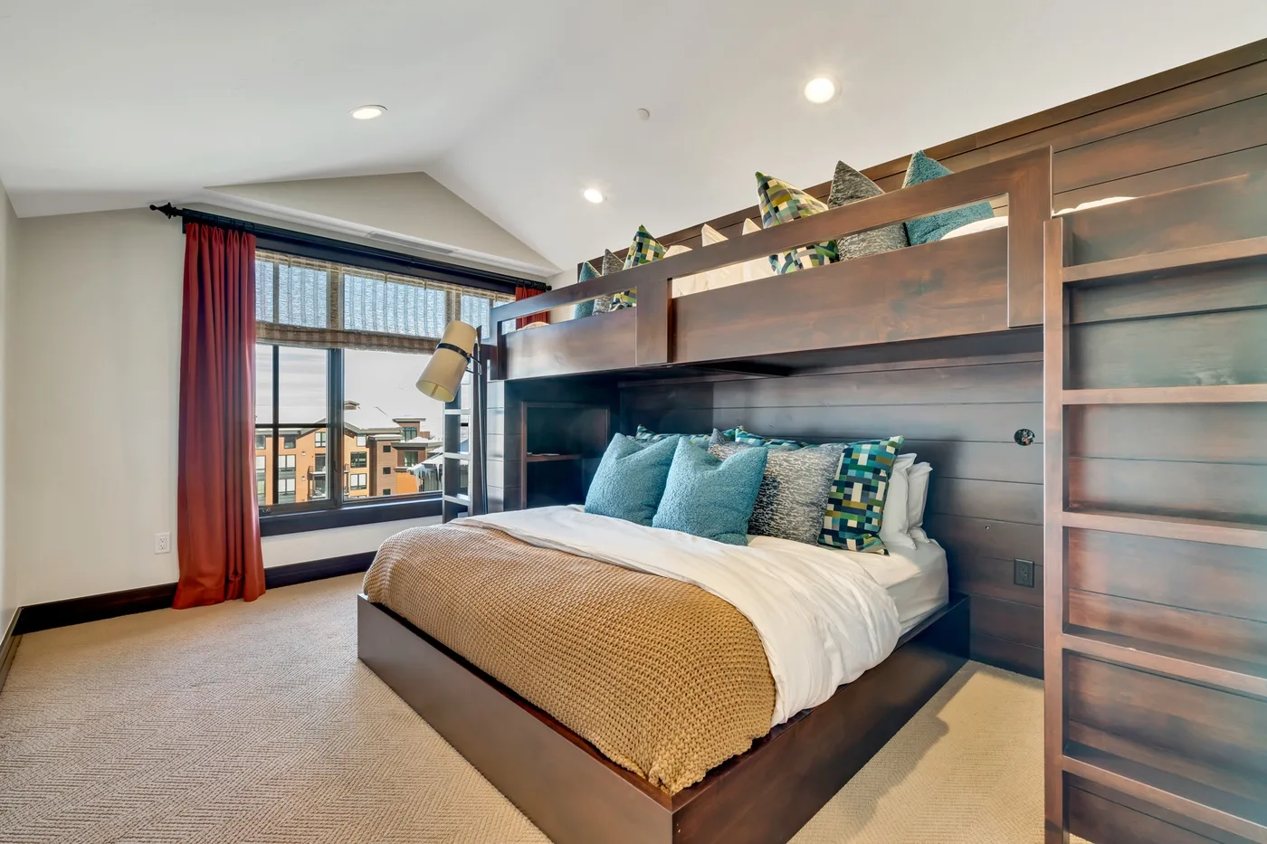 A bedroom with a large bed beneath a wooden loft structure.