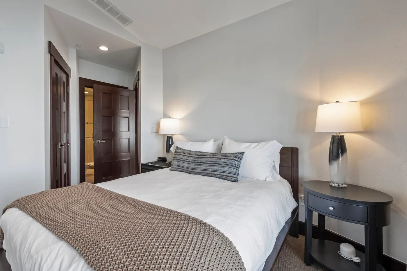 A bedroom with a neatly made bed and matching bedside lamps.