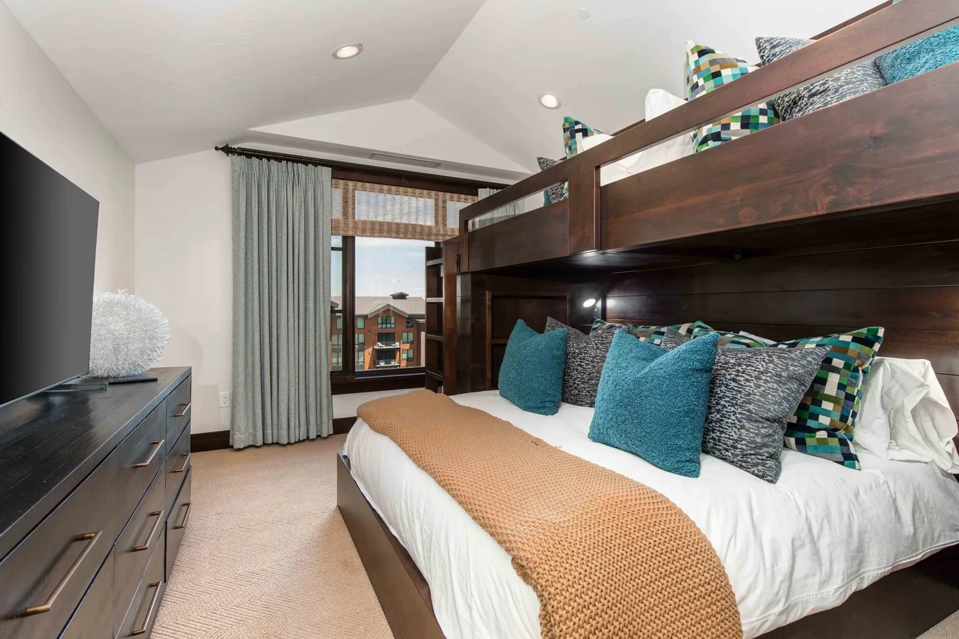 A bedroom with a large bed beneath a dark wooden loft structure.