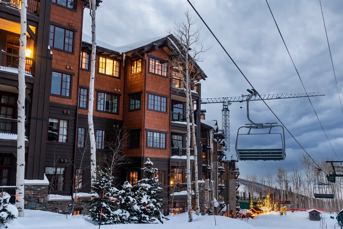 A snow-covered lodge stands beside a ski lift under a cloudy winter sky.