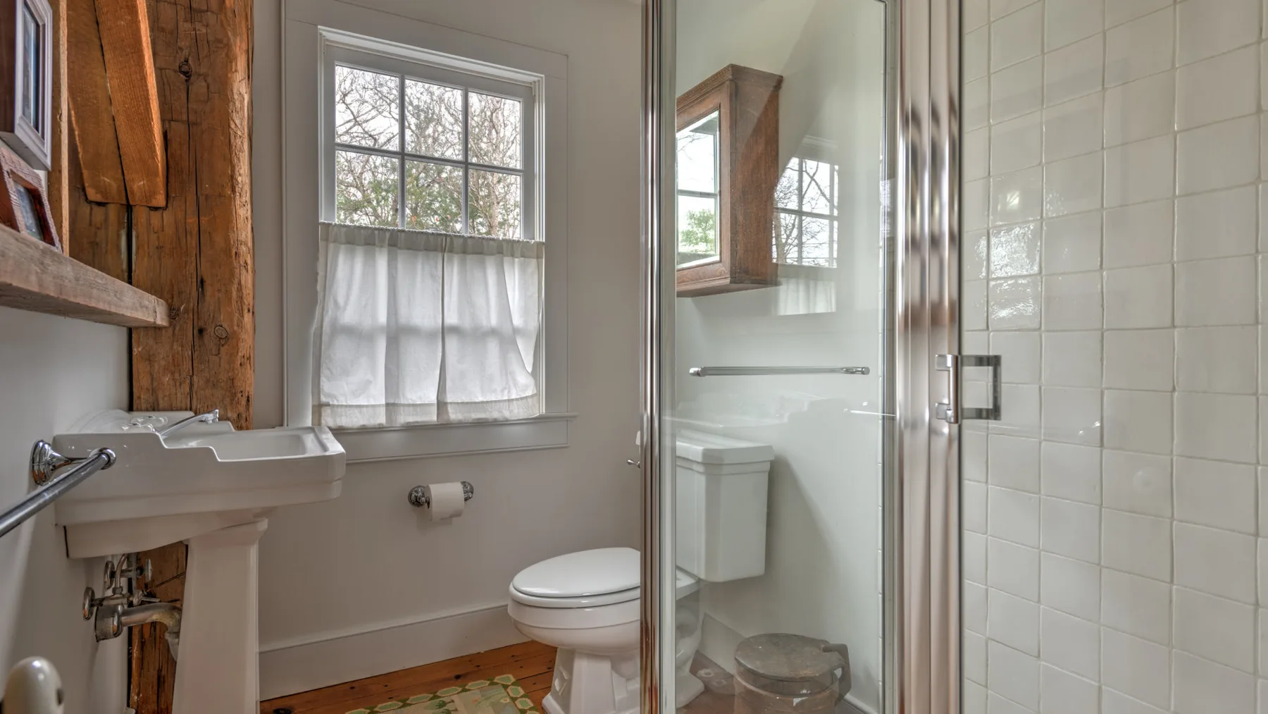 Un baño con lavabo de pedestal, inodoro y ducha con mampara de vidrio.