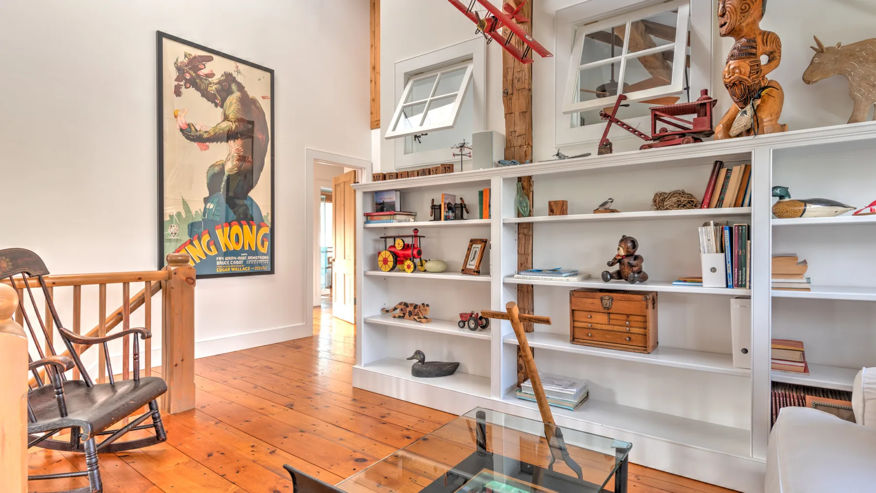 Una habitación luminosa con estanterías blancas empotradas llenas de libros y objetos decorativos.