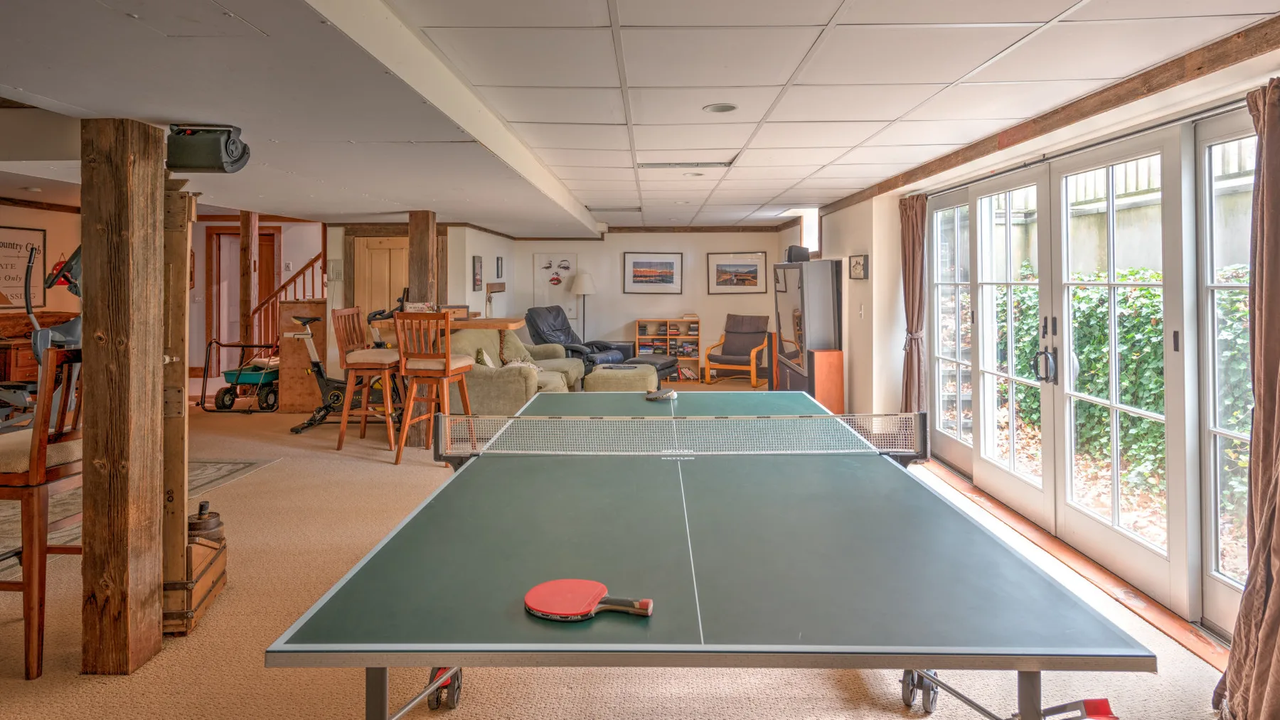 Una amplia sala de recreación tiene una mesa de tenis de mesa junto a grandes ventanas.