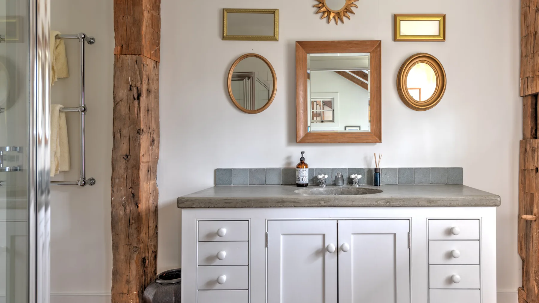 Un baño luminoso con lavabo, espejos y una ducha de vidrio.