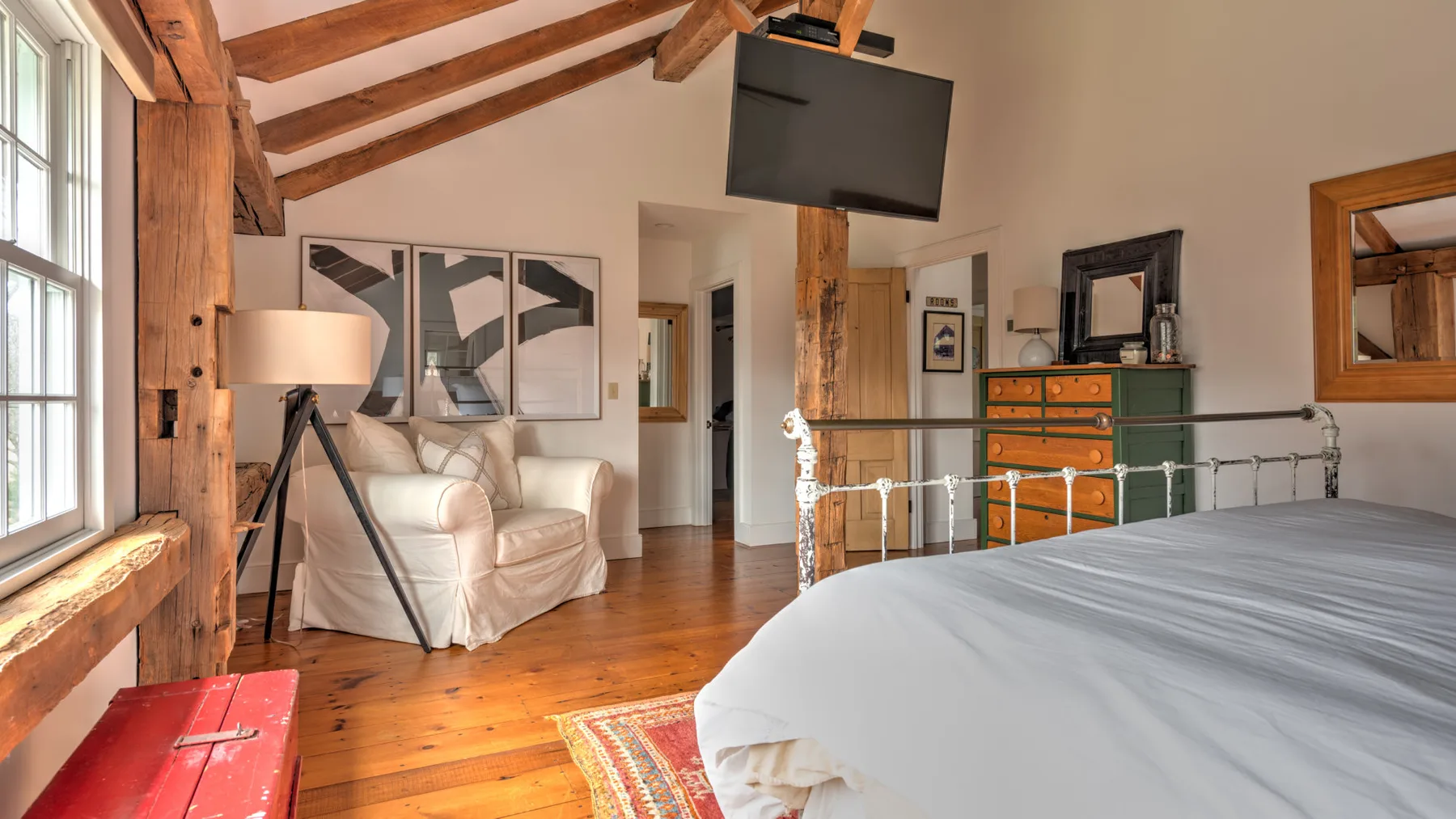 Un dormitorio con cama, asientos y vigas de madera a la vista.