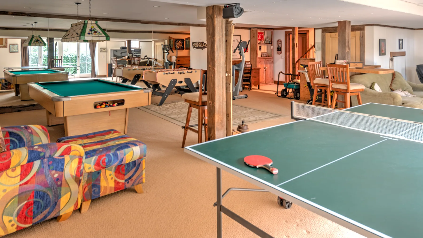 Una sala de juegos con mesas de billar, una mesa de ping-pong y asientos.