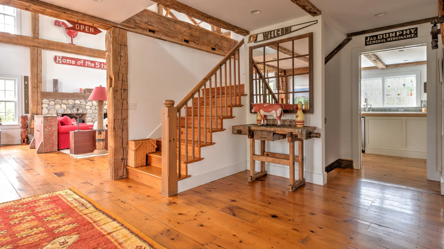 Interior con entramado de madera, una escalera de madera y una pequeña mesa consola.