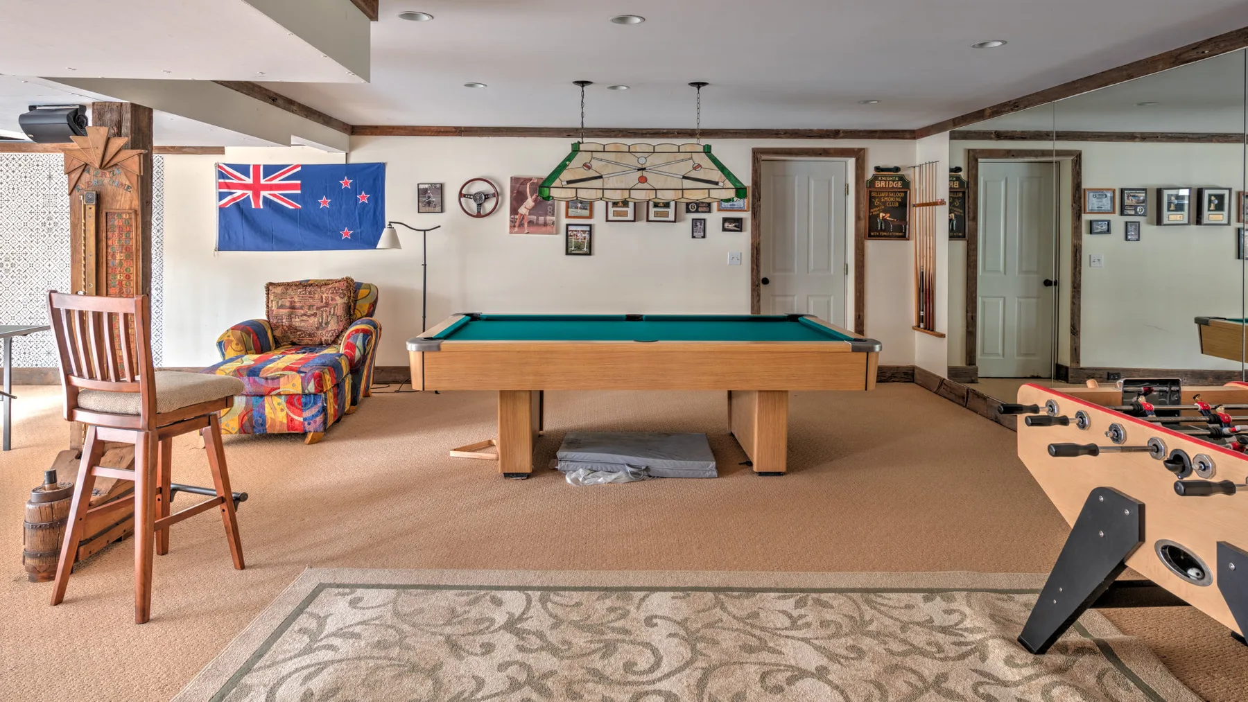 Una sala de juegos con mesa de billar, asientos coloridos y futbolín.