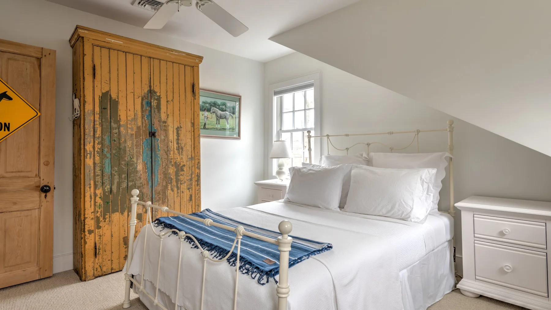 Un dormitorio con una cama blanca y un armario de madera.
