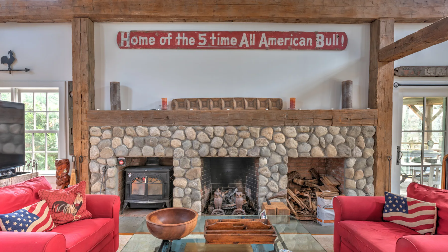 Una sala rústica con asientos rojos alrededor de una chimenea de piedra.