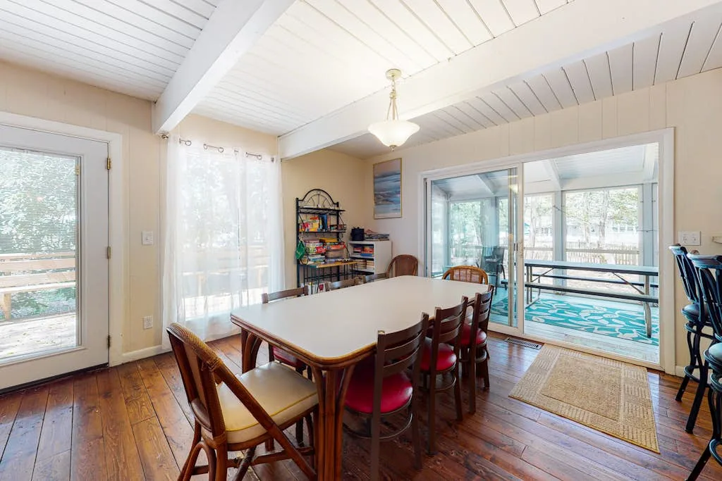 Comedor con mesa y sillas junto a puertas corredizas de vidrio que dan a una piscina.