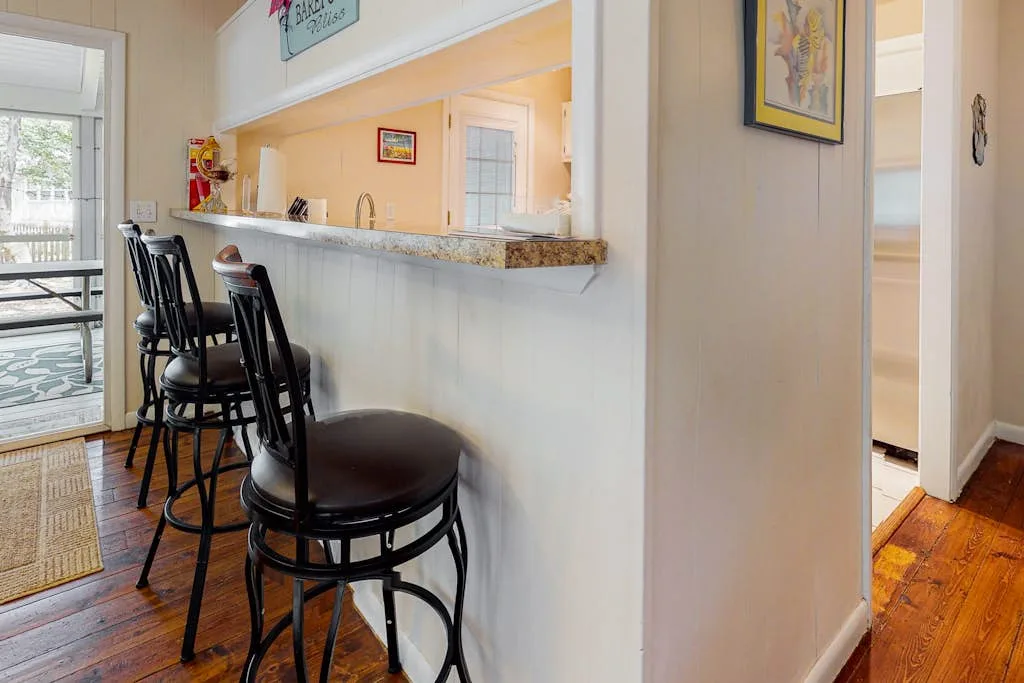 A kitchen counter with dark bar seating and a bright adjoining dining area.