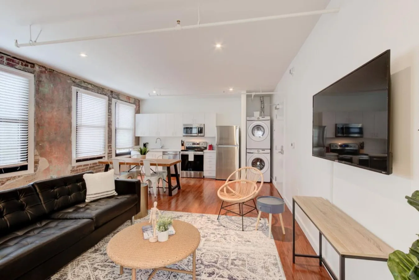 Una sala de estar y cocina de planta abierta con mesa de comedor y televisor en la pared.