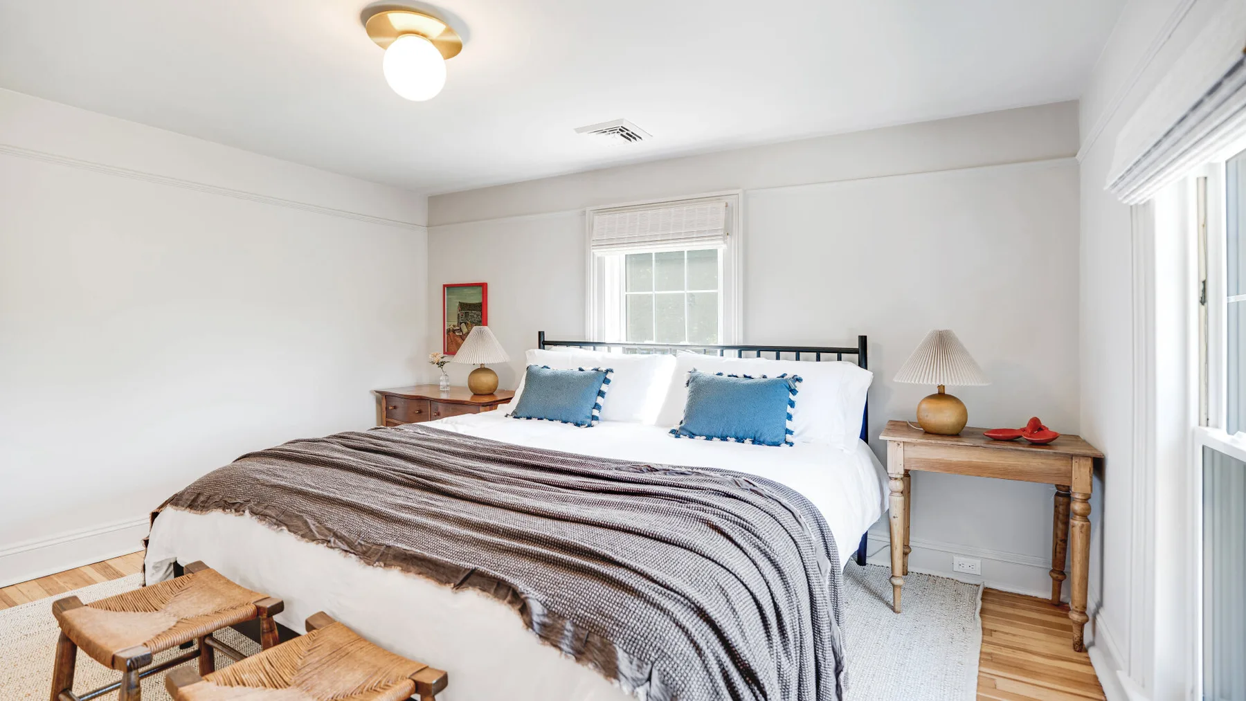 A bedroom with a bed, white bedding, and a brown throw.