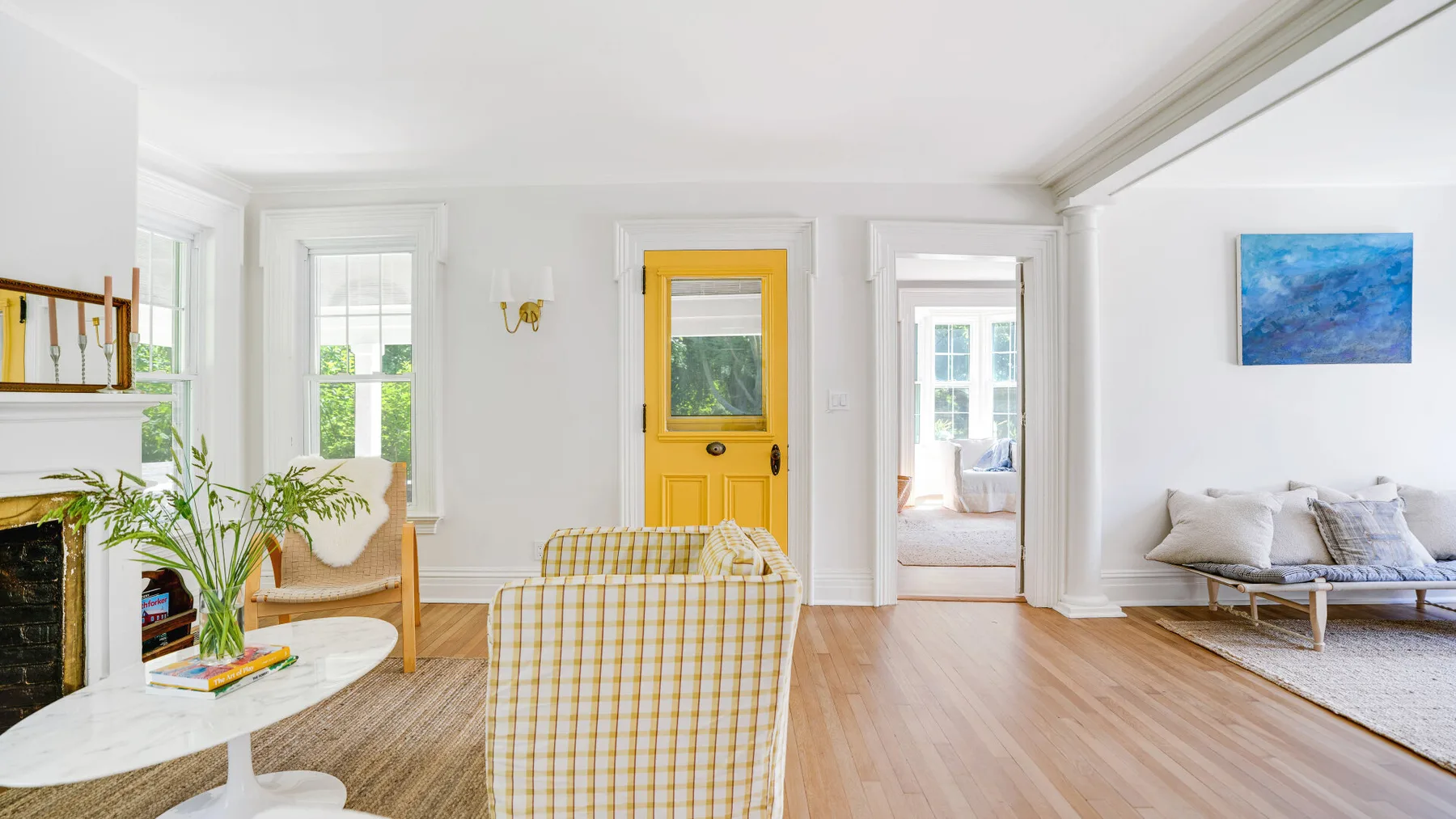 A bright living room with seating, a fireplace, and a yellow door.