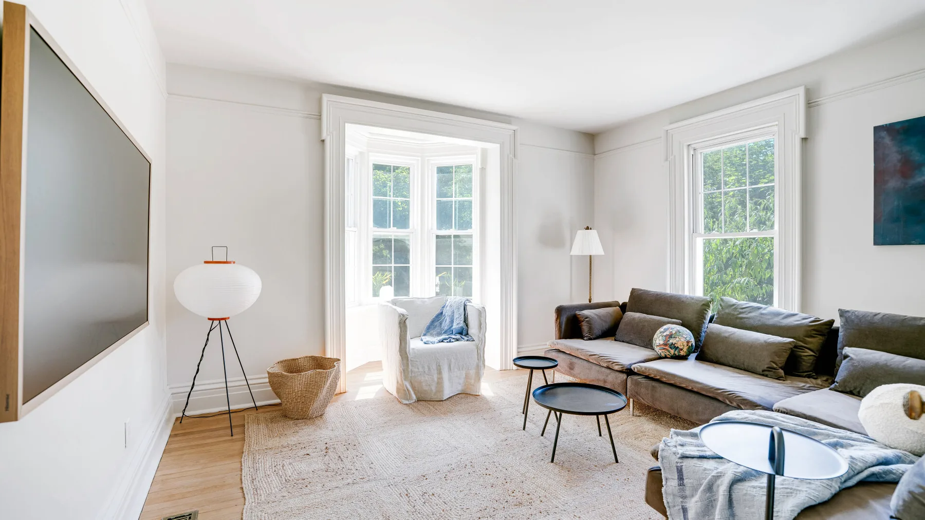 A bright living room with seating, two large windows, and a light area rug.