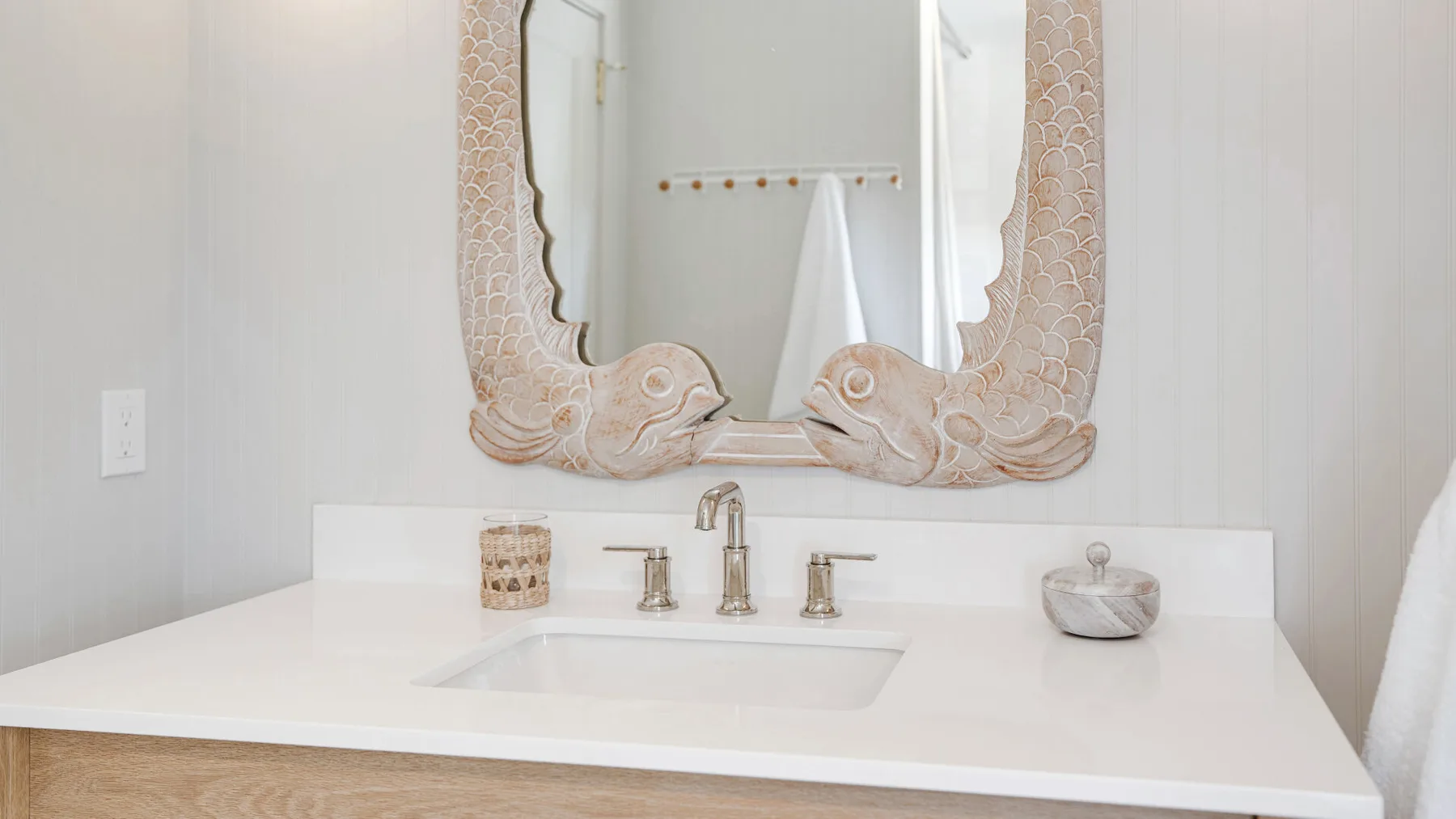 A bathroom vanity with a sink beneath an ornate wall mirror.
